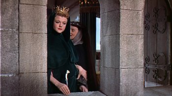 Movie still from “The Court Jester” (1955), directed by Melvin Frank – A woman wearing a crown standing next to another woman; Medium shot, Low angle
