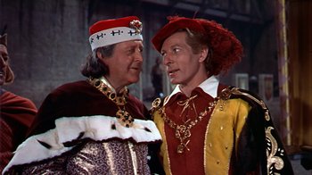 Movie still from “The Court Jester” (1955), directed by Melvin Frank – Two men dressed in medieval costumes , one of which is wearing a crown and the other is wearing a hat; Medium shot, Over the shoulder angle