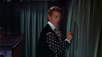 Movie still from “The Court Jester” (1955), directed by Melvin Frank – A man wearing a suit and tie standing in front of a curtain; Medium shot, Low angle