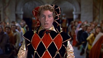 Movie still from “The Court Jester” (1955), directed by Melvin Frank – A man in a jester costume standing in front of a crowd of onlookers; Medium shot, Low angle