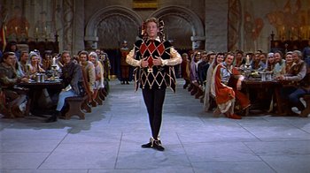 Movie still from “The Court Jester” (1955), directed by Melvin Frank – A man dressed in medieval garb stands in front of a crowd; Wide shot, High angle