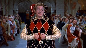 Movie still from “The Court Jester” (1955), directed by Melvin Frank – A man dressed as a harlequin holding a heart; Medium shot, High angle