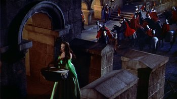 Movie still from “The Court Jester” (1955), directed by Melvin Frank – A woman in a green dress holding a basket in front of a group of people; Extreme Wide shot, High angle