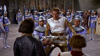 Movie still from “The Court Jester” (1955), directed by Melvin Frank – A group of people in costumes holding a bowl; Medium shot, High angle