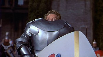 Movie still from “The Court Jester” (1955), directed by Melvin Frank – A man wearing a suit of armor and holding a board; Medium shot, Low angle
