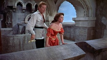 Movie still from “The Court Jester” (1955), directed by Melvin Frank – A man and a woman standing next to each other in front of a stone wall; Medium shot, Low angle
