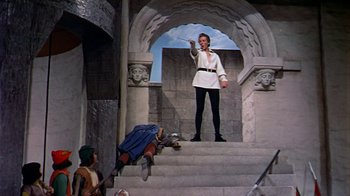 Movie still from “The Court Jester” (1955), directed by Melvin Frank – A man standing on a set of steps pointing to something; Wide shot, Low angle