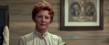 Movie still from “The Cowboys” (1972), directed by Mark Rydell – An older woman in a white shirt holding a book; Close Up shot, Low angle