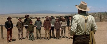 Movie still from “The Cowboys” (1972), directed by Mark Rydell – A group of men standing next to each other in a field; Wide shot, Over the shoulder angle
