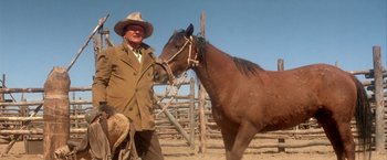 Movie still from “The Cowboys” (1972), directed by Mark Rydell – A man standing next to a horse in a corral; Medium shot, Over the shoulder angle