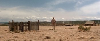 Movie still from “The Cowboys” (1972), directed by Mark Rydell – A man in a hat standing in the middle of a field; Extreme Wide shot, Low angle