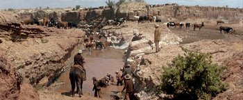 Movie still from “The Cowboys” (1972), directed by Mark Rydell – A group of men standing next to each other on top of a hill; Wide shot, High angle