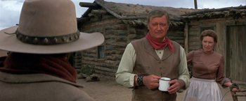 Movie still from “The Cowboys” (1972), directed by Mark Rydell – A man holding a cup in his hands; Medium shot, Over the shoulder angle