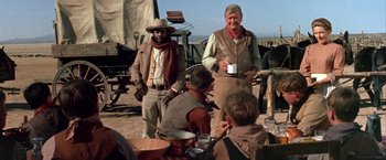 Movie still from “The Cowboys” (1972), directed by Mark Rydell – A group of men standing next to each other on a dirt field; Medium shot, Over the shoulder angle