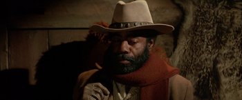 Movie still from “The Cowboys” (1972), directed by Mark Rydell – A man with a beard and a cowboy hat; Close Up shot, Low angle