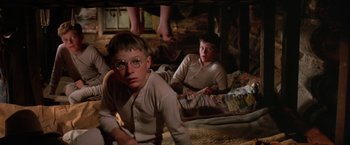 Movie still from “The Cowboys” (1972), directed by Mark Rydell – Two young boys are sitting on the floor; Medium shot, Low angle