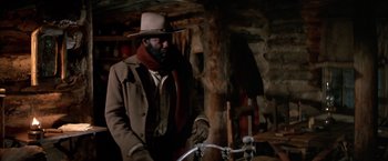 Movie still from “The Cowboys” (1972), directed by Mark Rydell – A man wearing a hat and a long brown coat; Medium shot, Low angle