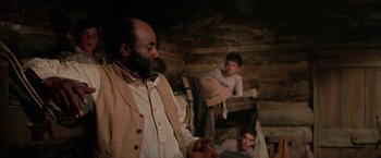 Movie still from “The Cowboys” (1972), directed by Mark Rydell – A man in a white shirt and a man in a brown vest; Medium shot, Over the shoulder angle