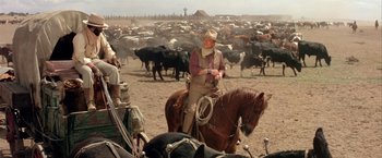 Movie still from “The Cowboys” (1972), directed by Mark Rydell – A man on a horse in front of a herd of cattle; Wide shot, Over the shoulder angle