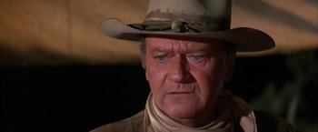 Movie still from “The Cowboys” (1972), directed by Mark Rydell – An older man wearing a cowboy hat and a neck tie; Close Up shot, Over the shoulder angle