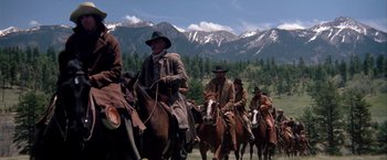 Movie still from “The Cowboys” (1972), directed by Mark Rydell – A group of men on horses in a field; Wide shot, Low angle
