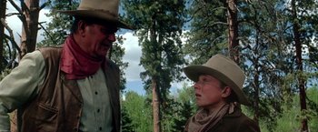 Movie still from “The Cowboys” (1972), directed by Mark Rydell – A man and a woman wearing cowboy hats; Medium shot, Over the shoulder angle