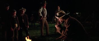 Movie still from “The Cowboys” (1972), directed by Mark Rydell – A group of men standing next to each other in the dark; Medium shot, Low angle