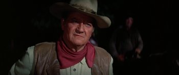 Movie still from “The Cowboys” (1972), directed by Mark Rydell – A man wearing a cowboy hat and neck scarf; Close Up shot, Low angle