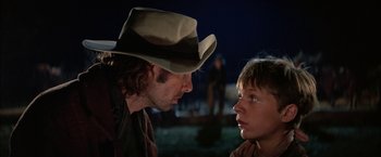 Movie still from “The Cowboys” (1972), directed by Mark Rydell – A man and a boy are looking at one another; Close Up shot, Over the shoulder angle