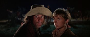 Movie still from “The Cowboys” (1972), directed by Mark Rydell – A man and a boy wearing a cowboy hat; Close Up shot, Low angle