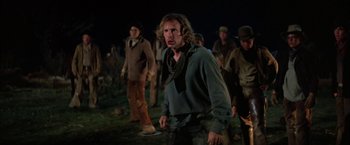 Movie still from “The Cowboys” (1972), directed by Mark Rydell – A group of people walking in a field at night; Medium shot, Low angle