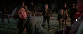 Movie still from “The Cowboys” (1972), directed by Mark Rydell – A group of people standing around in a field; Medium shot, Over the shoulder angle