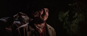 Movie still from “The Cowboys” (1972), directed by Mark Rydell – A man wearing a black hat and a brown jacket; Close Up shot, Low angle