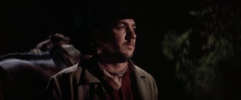 Movie still from “The Cowboys” (1972), directed by Mark Rydell – A man wearing a cowboy hat in a dark room; Close Up shot, Low angle