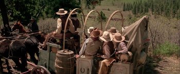 Movie still from “The Cowboys” (1972), directed by Mark Rydell – A group of men riding on top of a wagon; Wide shot, High angle
