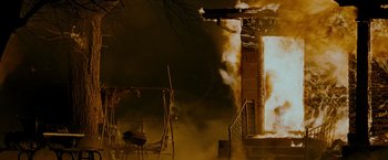 Movie still from “The Crazies” (2010), directed by Breck Eisner – A house that is on fire with smoke billowing out of it; Wide shot, Low angle