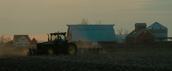 Movie still from “The Crazies” (2010), directed by Breck Eisner – A tractor is driving in a field near a barn; Extreme Wide shot, Low angle