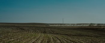 Movie still from “The Crazies” (2010), directed by Breck Eisner – A car driving on a dirt road near a field; Extreme Wide shot, High angle