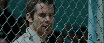 Movie still from “The Crazies” (2010), directed by Breck Eisner – A person behind a chain link fence; Close Up shot, Over the shoulder angle