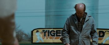 Movie still from “The Crazies” (2010), directed by Breck Eisner – A man standing in front of an advertisement; Medium shot, Low angle