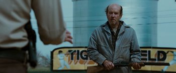 Movie still from “The Crazies” (2010), directed by Breck Eisner – A man holding a gun while standing next to another man; Medium shot, Over the shoulder angle