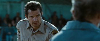 Movie still from “The Crazies” (2010), directed by Breck Eisner – A man in a police uniform looking at someone; Close Up shot, Over the shoulder angle