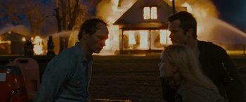 Movie still from “The Crazies” (2010), directed by Breck Eisner – Two people standing in front of a burning house; Medium shot, Over the shoulder angle
