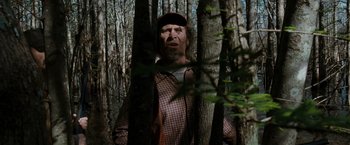 Movie still from “The Crazies” (2010), directed by Breck Eisner – A man standing next to a tree in the woods; Medium shot, Low angle