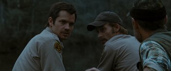 Movie still from “The Crazies” (2010), directed by Breck Eisner – Two men standing next to each other in a forest; Close Up shot, Over the shoulder angle