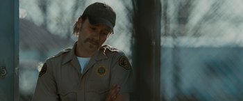 Movie still from “The Crazies” (2010), directed by Breck Eisner – A man in a sheriff's uniform looking down at his arm; Close Up shot, Over the shoulder angle