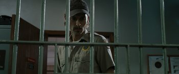 Movie still from “The Crazies” (2010), directed by Breck Eisner – A man standing behind bars in front of a window; Close Up shot, Low angle