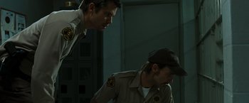 Movie still from “The Crazies” (2010), directed by Breck Eisner – Two men in uniform looking at each other in a dark room; Medium shot, Low angle