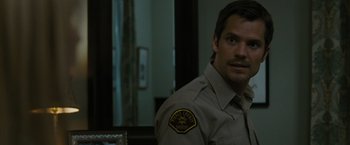 Movie still from “The Crazies” (2010), directed by Breck Eisner – A man in a police uniform is looking at the camera; Close Up shot, Over the shoulder angle