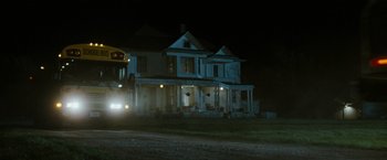 Movie still from “The Crazies” (2010), directed by Breck Eisner – A house that has a bus in front of it at night time; Extreme Wide shot, Low angle